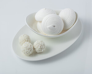 White marshmallows and candies with coconut on a white bowl