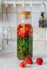 Strawberry lemonade with mint. Ingredients for lemonade in a bottle on white background. Strawberry, lemon zest, peppermint, water.