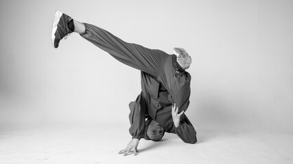 A man hip hop dancer or bboy freezes in one pose on a white background. Bboy doing stylish stunts.