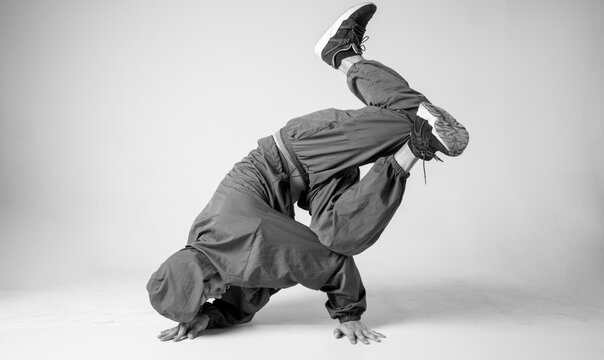 A man hip hop dancer or bboy freezes in one pose on a white background. Bboy doing stylish stunts.