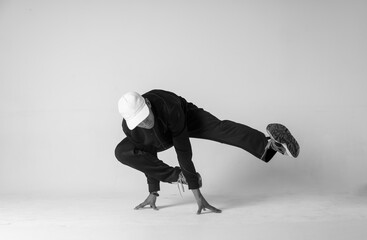 A man hip hop dancer or bboy freezes in one pose on a white background. Bboy doing stylish stunts.