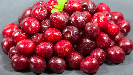 A bunch of cherries on a gray background. Vitamin seasonal food, for a vegetarian. Ripe cherry with mint leaves for a cocktail.