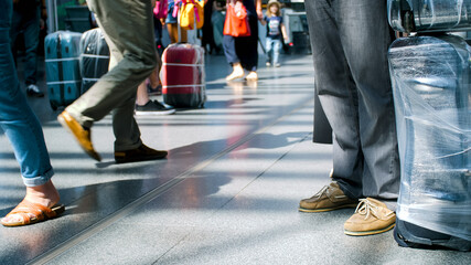 Fototapeta premium Feet of tourists with luggage standing in long line at airport terminal