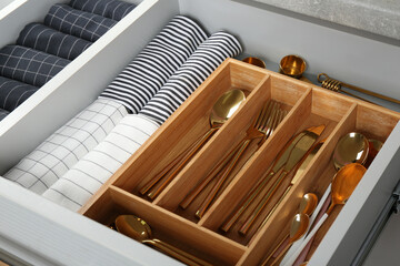Fototapeta na wymiar Open drawer with different utensils and folded towels. Order in kitchen