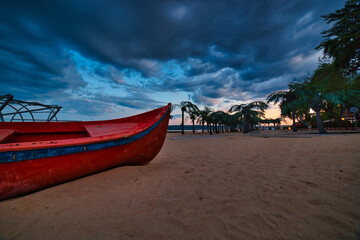 A boat on a beach with sunset and clouds