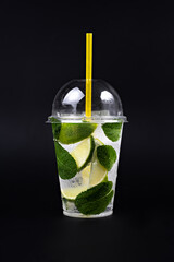 Lemonade to go cup with mint and lime on black background, isolated