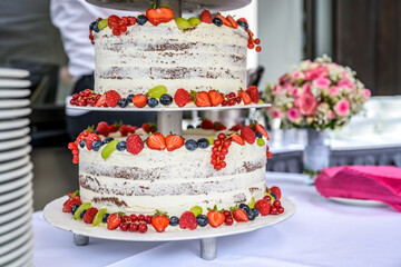 Obraz na płótnie Canvas beautiful delicious Wedding cake in many tiers with fresh wild berries and fruits