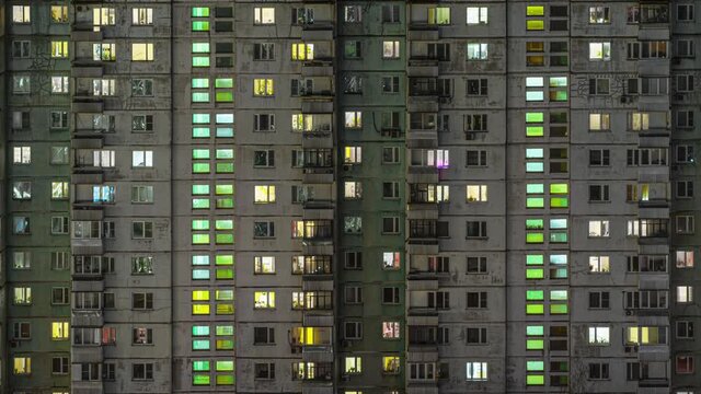 Beautiful aerial timelapse of multi-storey building facade in the evening. Windows beautifully glittering with its lights while people staying at home doing their stuff.