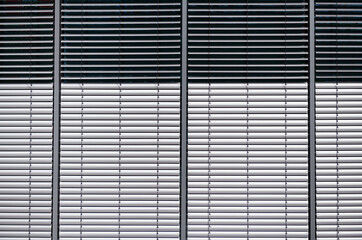 Silver jalousies at four windows of a modern office building