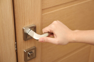 Woman opening door indoors, closeup of hand