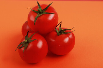  tomates maduros rojos sobre fondo de color puestos en forma de pirámide