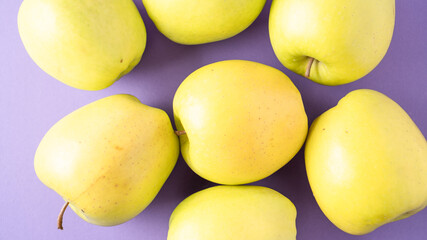 Yellow apples on purple background. Set of green apples. Scattered ripe juicy apples. Healthy snack. Bright colors.