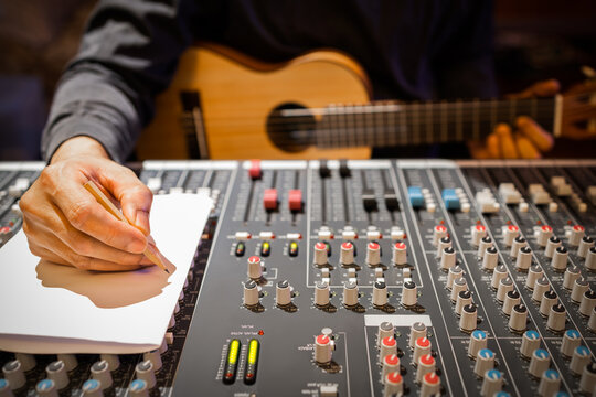 male composer hands writing a song on white paper in recording studio