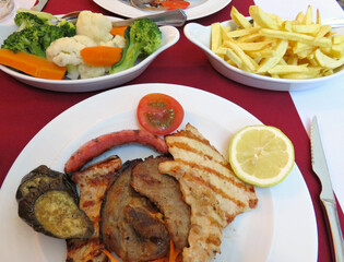 Traditional Portuguese grilled meat platter with french fries and vegetables 