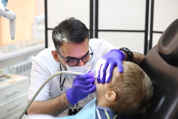 dentist is diagnosing the child while assistant in dental clinic