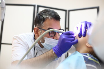 dentist is diagnosing the child while assistant in dental clinic
