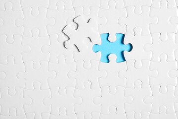 Blank white puzzle with separated piece on light blue background, top view