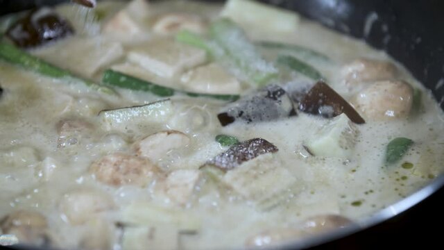 Adding Table Spoon of Salt Sugar from small Blue Bowl to Boiling Thai Vegetable Curry