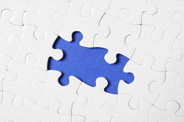 Blank white puzzle with missing pieces on blue background, top view
