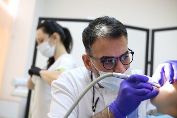 dentist is diagnosing the child while assistant in dental clinic