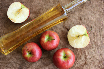 Homemade apple cider and fresh apples on a burlap background, top view, copy space.
