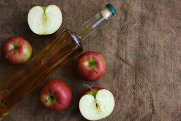 Homemade apple cider and fresh apples on a burlap background, top view, copy space.
