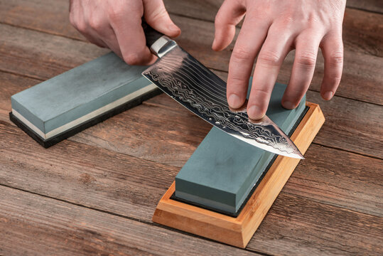 Man sharpening a Japanese chef's knife with a wet whetstone