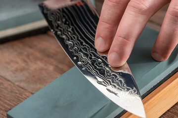 Close-up on a Damascus steel blade being sharpened with a whetstone