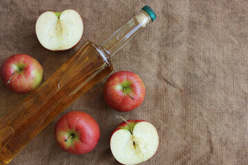 Homemade apple cider and fresh apples on a burlap background, top view, copy space.
