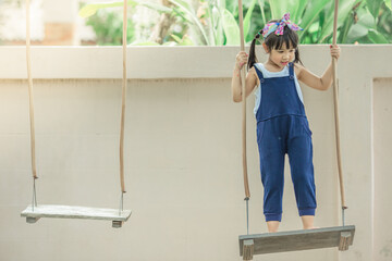 Close-up background view Of cute girls, sitting on the swing and swinging with force, learning between ages or physical exercise for good health