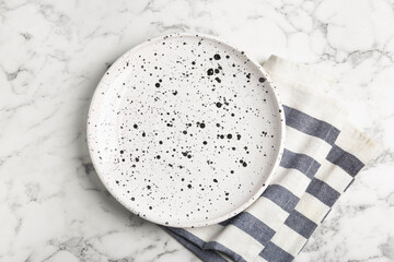 Empty patterned plate and napkin on white marble table, flat lay
