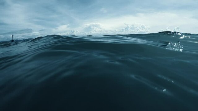 Wave on moving water surface closeup in the middle of the screen.  Reach Back to the Water Surface in the middle of the sea
