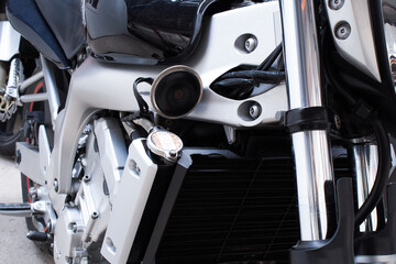 Close-up of air filter, radiator, chrome frame of motorcycle. Water, liquid cooling, front fork, signal, tank, sport bike engine in the workshop. Color photo from a low angle of a road bike in garage