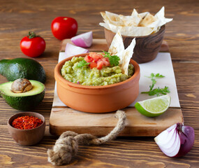 Guacamole dip in ceramic bowl and ingredients. Mexican cuisine