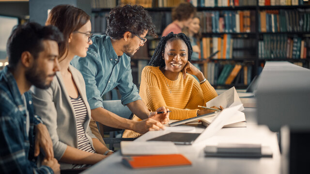University Library: Diverse Group of Gifted Students Have Discussion, use Laptop, Prepare for Exams Together, Helping, Researching Subjects for Paper Assignment. Happy Young People Study for Future