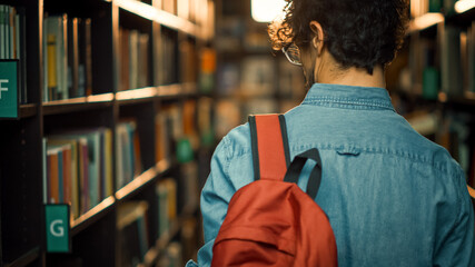 University Library: Student Walks Between Rows of Bookshelves Searching for Right Book Title for...