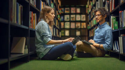 University Library: Smart Caucasian Girl Sitting and Talented Hispanic Boy Sitting Cross-Legged On the Floor, Talk, Use Laptops and Discuss Paper, Study and Prepare for Exams Together