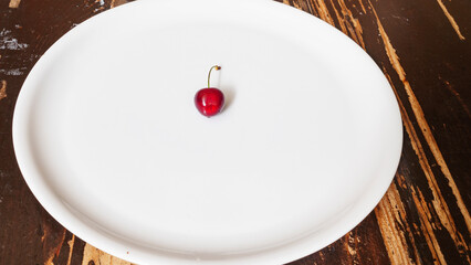 Top view of a cherry berry on a white plate. Ripe cherrie texture. Space for text.