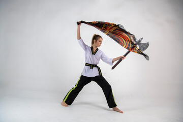 beautiful girl in a white-black suit does exercises with a battle ax and a scarf