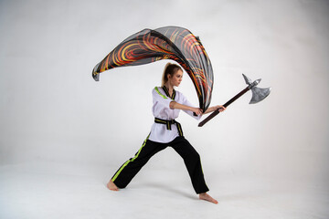Fototapeta na wymiar beautiful girl in a white-black suit does exercises with a battle ax and a scarf