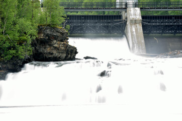 massive white waterfall down rocks as water power plant opens concrete barrier
