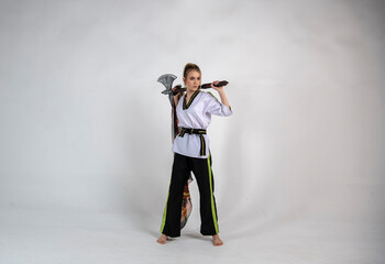 beautiful girl in a white-black suit does exercises with a battle ax and a scarf