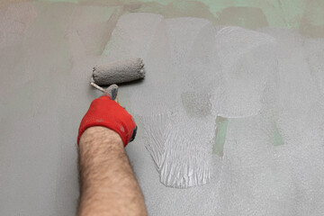 A close-up view of an experienced construction worker applying damp insulation using a paint roller...