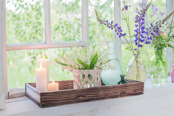 flowers with burning candles on white windowsill