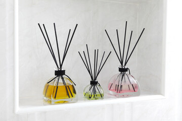 luxury glass aroma reed diffuser bottle with yellow and pink colour oil are displayed in the white toilet of the hotel resort during summer holiday in Maldives with happy family