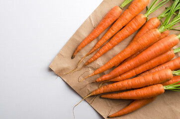Top view of fresh and young carrots on the craft brown pape, white table.Empty space