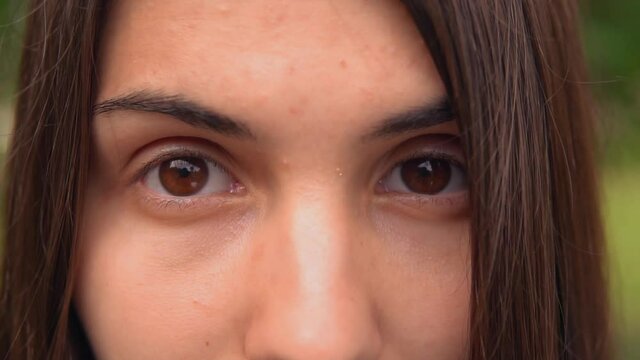 close up upper face young beautiful woman brown eyes looking at the camera slow motion