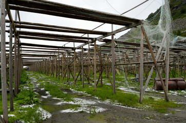 empty wooden stockfish structure with small salt piles on the green ground