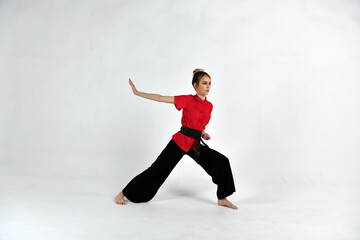 beautiful girl in a red-black suit does exercises in the style of martial arts