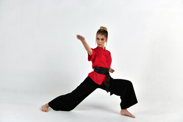 beautiful girl in a red-black suit does exercises in the style of martial arts